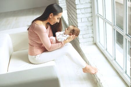 Beautiful woman with a baby is resting in a cozy house.の写真素材