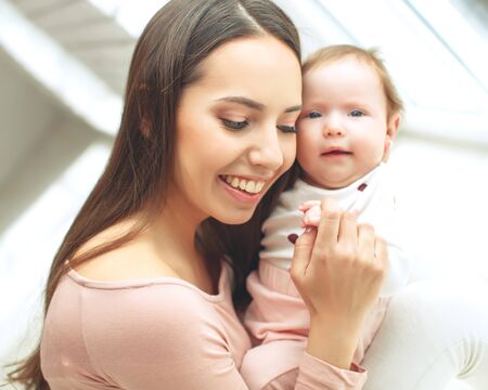 Beautiful woman with a baby is resting in a cozy house.の写真素材