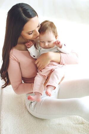 Beautiful woman with a baby is resting in a cozy house.の写真素材