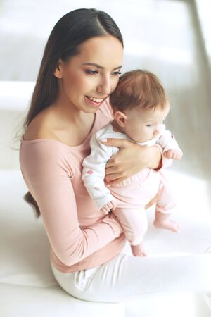 Beautiful woman with a baby is resting in a cozy house.の写真素材