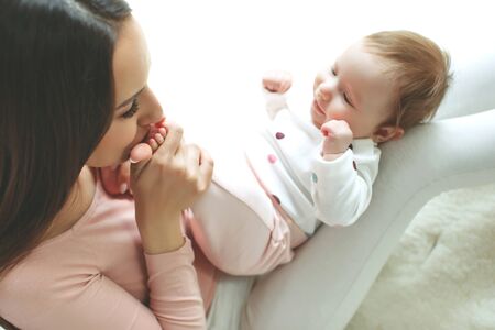 Beautiful woman with a baby is resting in a cozy house.の写真素材