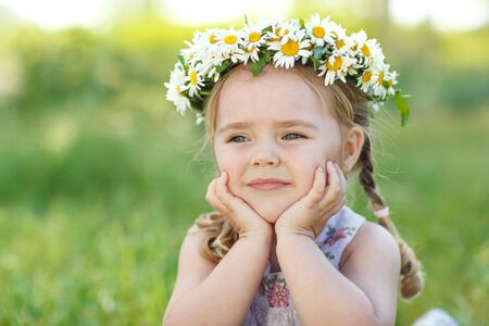 Little girl in nature with a wreath of flowers on her head.の写真素材