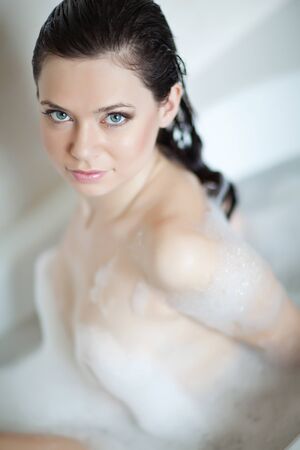 Beautiful woman takes a bath with foam at home.の写真素材