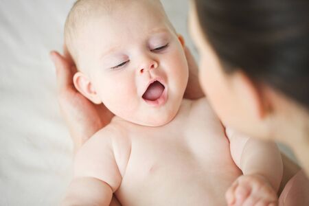 Woman with a baby on a white background. Mom holds the baby.の写真素材