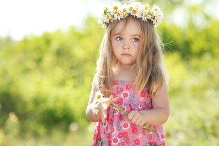 Little girl in nature with a wreath of flowers on her head.の写真素材