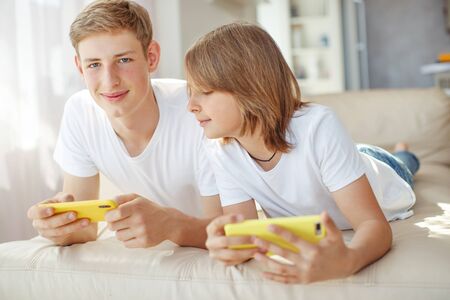 Children teenagers play a game on the phone at home.の写真素材