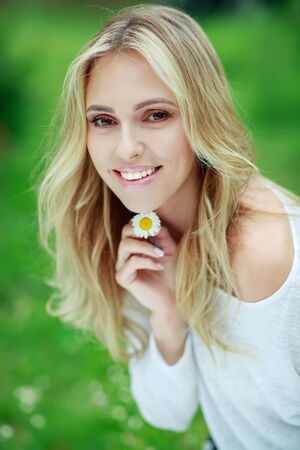Beautiful woman with a flower. Girl with camomiles. Beautiful woman portrait.の写真素材