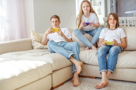 Children teenagers play a game on the phone at home.の写真素材