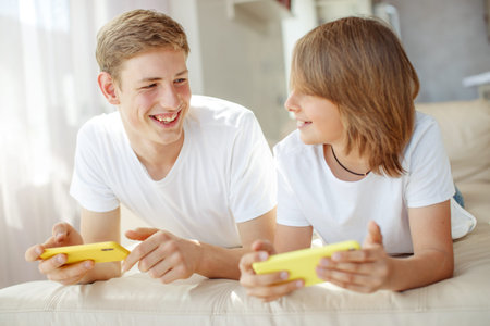 Children teenagers play a game on the phone at home.