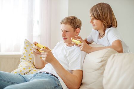 Children teenagers play a game on the phone at home.の写真素材