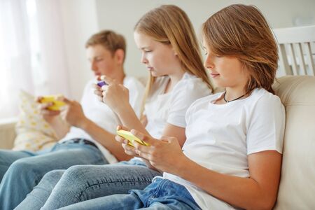 Children teenagers play a game on the phone at home.の写真素材