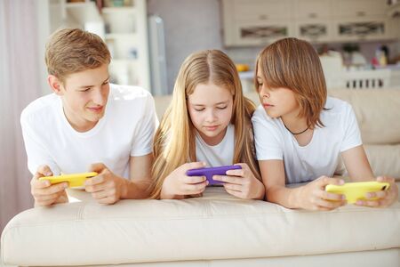 Children teenagers play a game on the phone at home.の写真素材