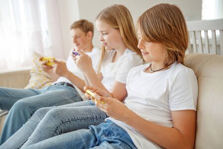 Children teenagers play a game on the phone at home.の写真素材