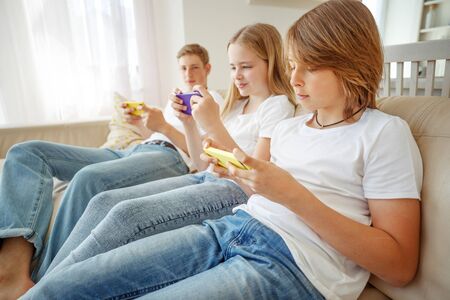 Children teenagers play a game on the phone at home.の写真素材