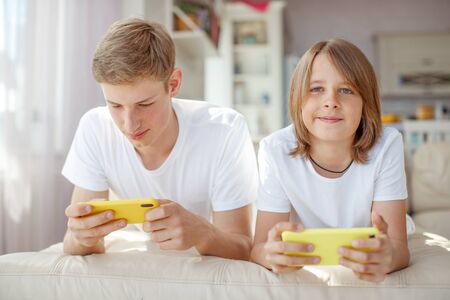 Children teenagers play a game on the phone at home.の写真素材