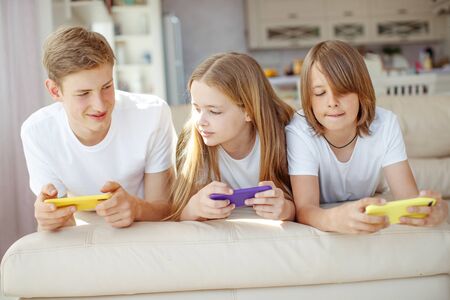 Children teenagers play a game on the phone at home.の写真素材