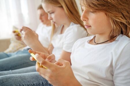 Children teenagers play a game on the phone at home.の写真素材