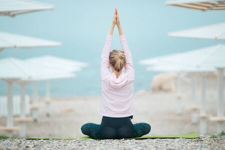 A woman practices yoga by the sea. Yoga girl. Young beautiful woman doing yoga poses in nature.の写真素材
