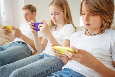 Children teenagers play a game on the phone at home.の写真素材