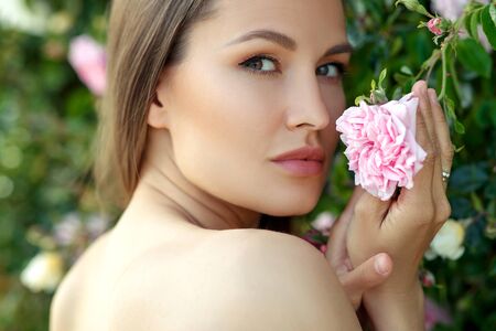 Beautiful young woman in nature in roses. Brunette girl with roses.の写真素材