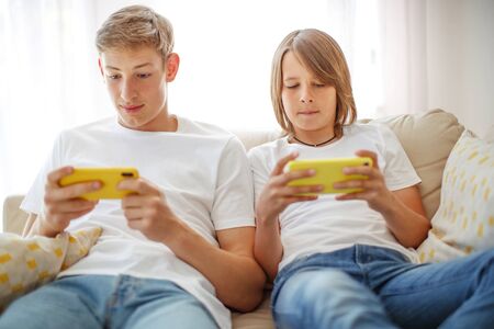 Children teenagers play a game on the phone at home.の写真素材