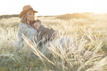 Mom with a child have fun playing in nature. A pregnant woman and a child are resting in nature.の写真素材