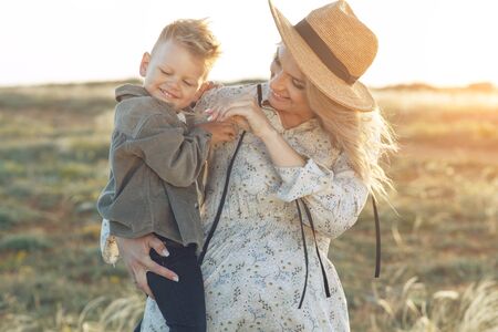 Mom with a child have fun playing in nature. A pregnant woman and a child are resting in nature.の写真素材