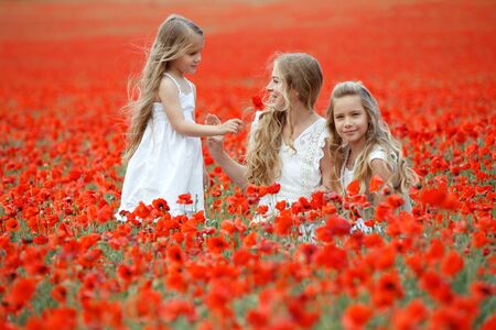 Woman with children in a field with flowers. Beautiful family on the nature.の写真素材