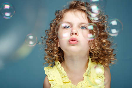 Child with soap bubbles. Little girl blowing soap bubbles in the studio. High quality photo.の写真素材