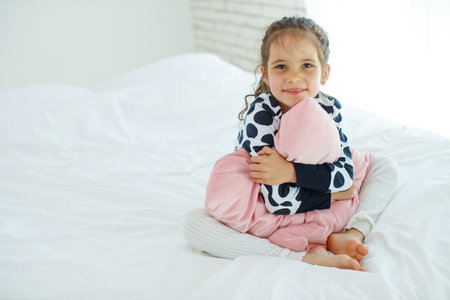 Little girl in bed. The child at home wakes up in bed in the morning. High quality photo.