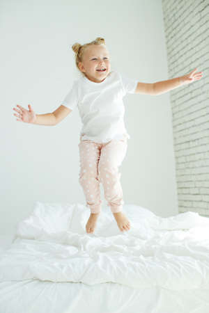 Little girl in bed with white linen. A child at home in the morning wakes up in his room. High quality photo.の写真素材