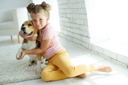 Child with a dog. Little girl plays with a dog at home. Child and animal. High quality photo.の写真素材