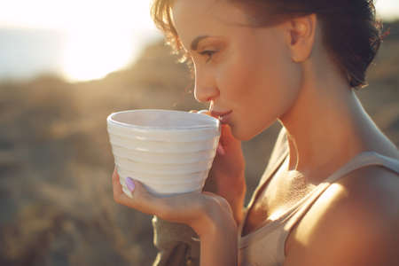 Beautiful woman drinks coffee. Woman outdoors. High quality photo.の写真素材