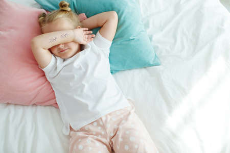 Little girl in bed with white linen. A child at home in the morning wakes up in his room. High quality photo.の写真素材