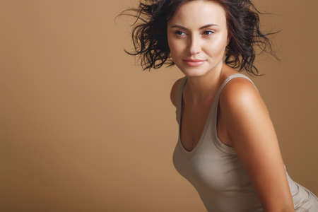 Beautiful woman in the studio. Bright portrait of a young girl on a beige background. High quality photo.の写真素材