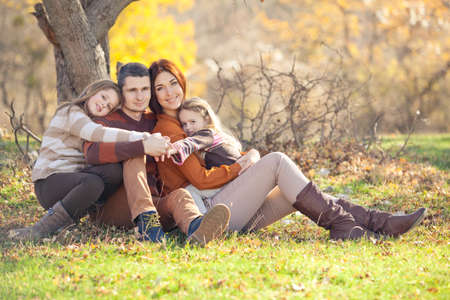 Family resting in nature in autumn. Beautiful woman with a man have fun playing with children. High quality photo.の写真素材