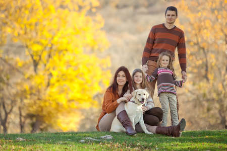Family resting in nature in autumn. Beautiful woman with a man have fun playing with children. High quality photo.の写真素材