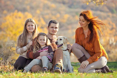 Family resting in nature in autumn. Beautiful woman with a man have fun playing with children. High quality photo.の写真素材