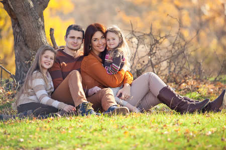 Family resting in nature in autumn. Beautiful woman with a man have fun playing with children. High quality photo.の写真素材