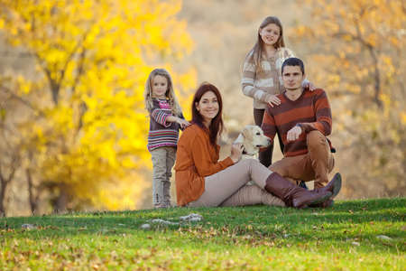 Family resting in nature in autumn. Beautiful woman with a man have fun playing with children. High quality photo.の写真素材