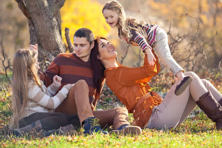 Family resting in nature in autumn. Beautiful woman with a man have fun playing with children. High quality photo.の写真素材