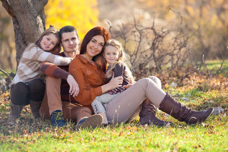 Family resting in nature in autumn. Beautiful woman with a man have fun playing with children. High quality photo.の写真素材