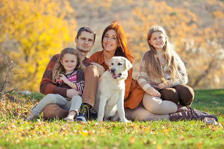 Family resting in nature in autumn. Beautiful woman with a man have fun playing with children. High quality photo.の写真素材
