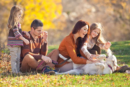 Family resting in nature in autumn. Beautiful woman with a man have fun playing with children. High quality photo.の写真素材