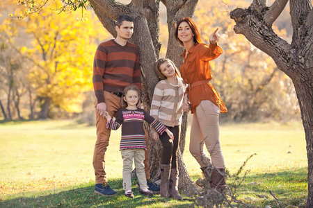 Family resting in nature in autumn. Beautiful woman with a man have fun playing with children. High quality photo.の写真素材