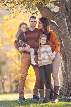 Family resting in nature in autumn. Beautiful woman with a man have fun playing with children. High quality photo.の写真素材