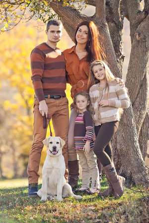 Family resting in nature in autumn. Beautiful woman with a man have fun playing with children. High quality photo.の写真素材