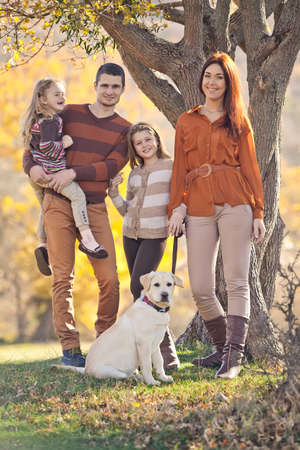 Family resting in nature in autumn. Beautiful woman with a man have fun playing with children. High quality photo.の写真素材