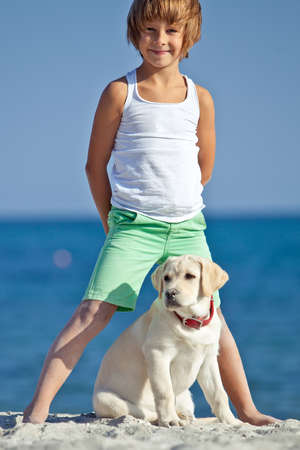 Happy boy playing with his dog on the seashore against the blue sky. Best friends have fun on vacation. High quality photo.の写真素材