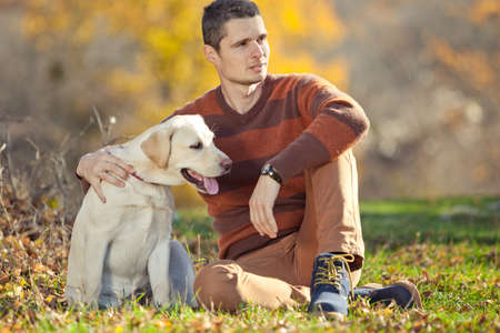 Dog and its owner a young man have fun in the park - Concepts of friendship, pets, togetherness. High quality photo.の写真素材